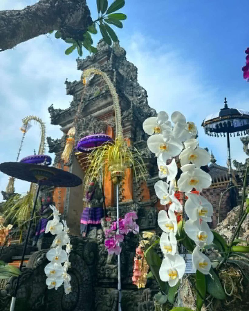 Ornate Balinese temple entrance decorated with white orchids and colorful umbrellas
