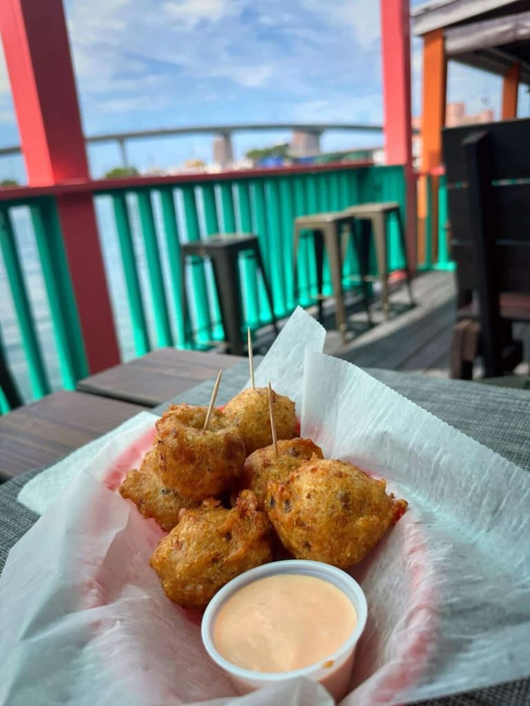 Conch fritters with dipping sauce on a table with a waterfront view in Nassau