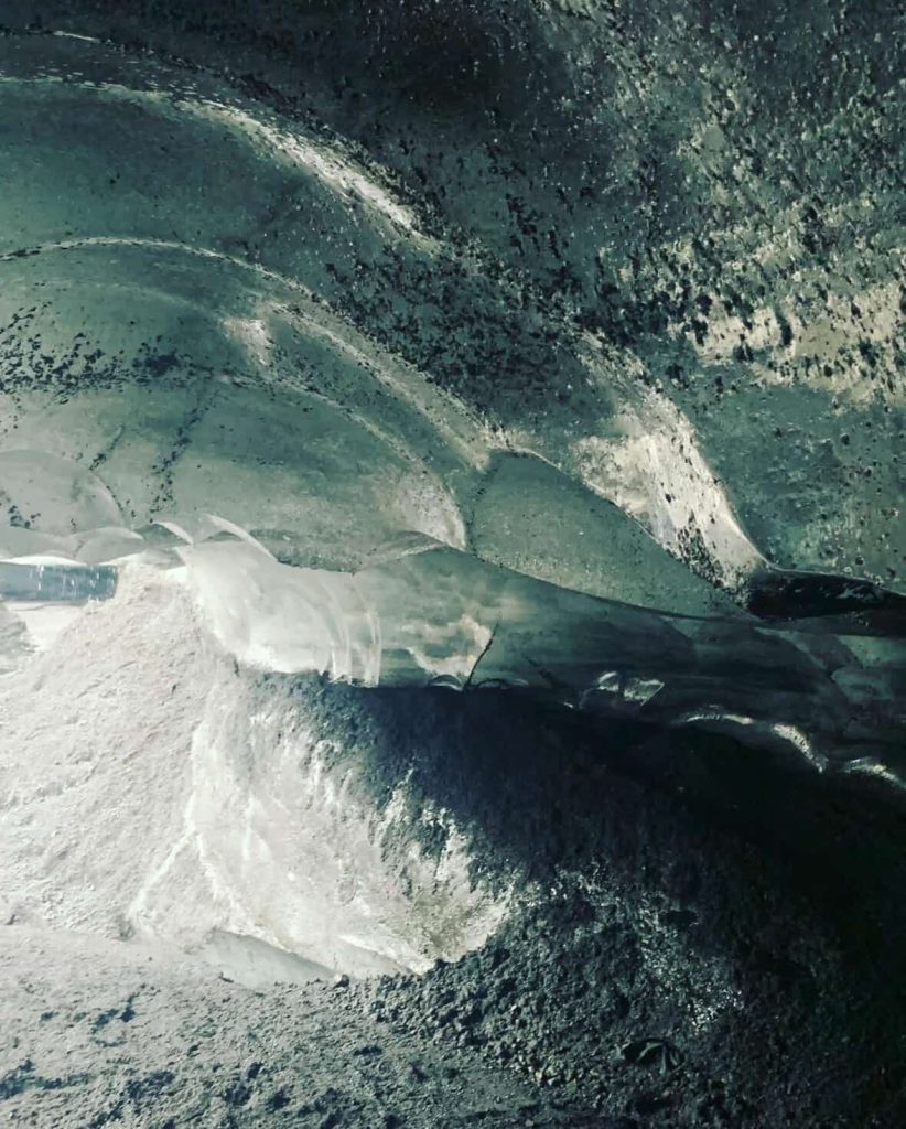 Inside an ice cave near Reykjavik, Iceland, with textures of ice and rock.
