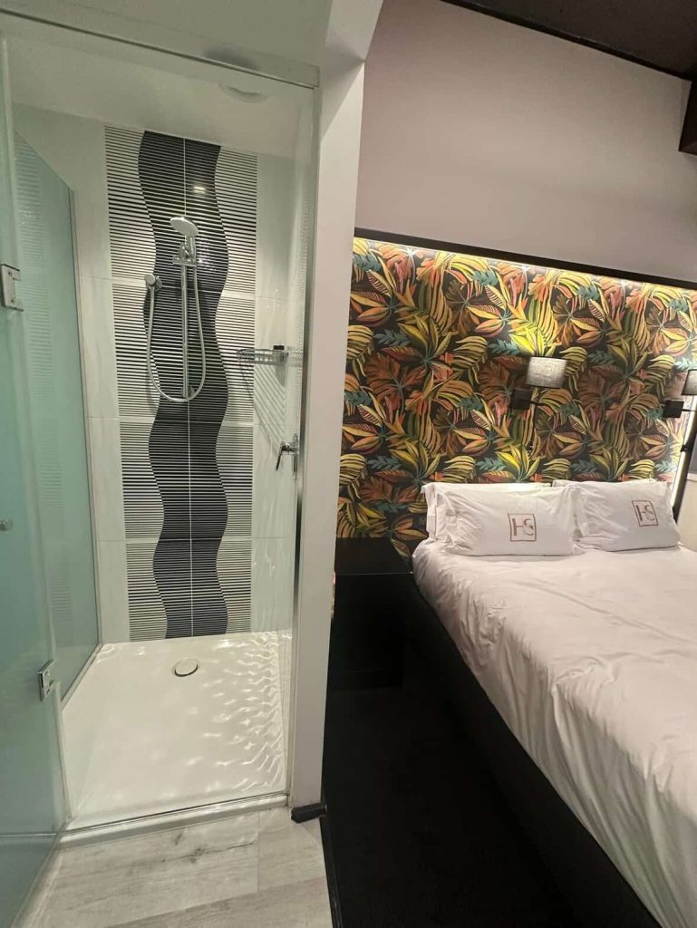 Modern hotel room with tropical wallpaper and a glass shower stall