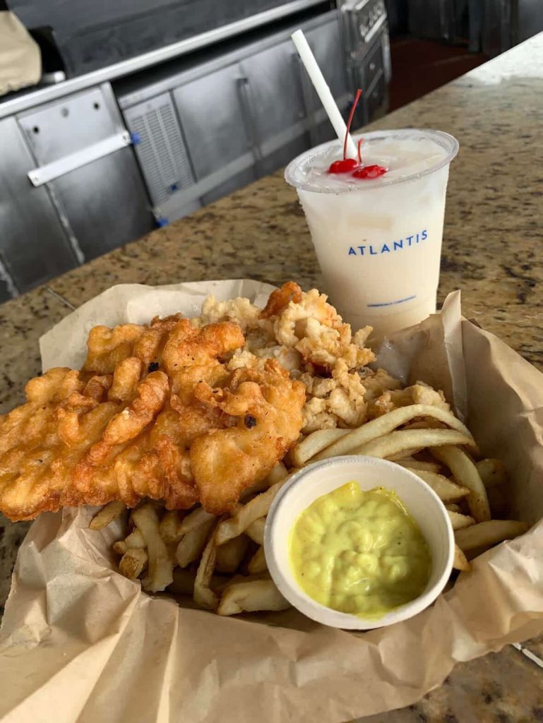 Atlantis Nassau seafood platter with fish, fries, and a piña colada