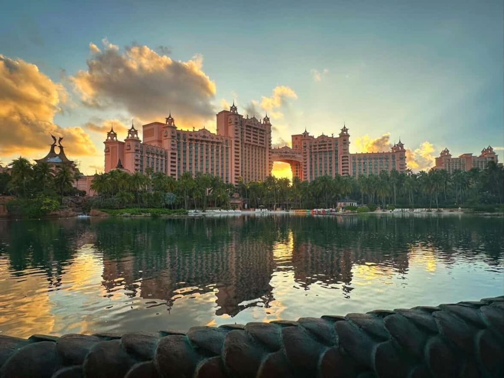 Atlantis Paradise Island resort in Nassau, Bahamas at sunset, reflected in the water.