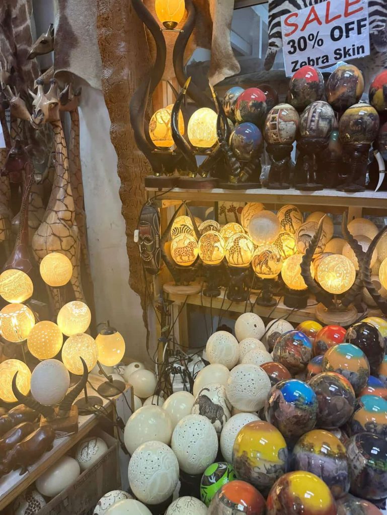 African ostrich egg lamps and carved wooden giraffes in a Cape Town market