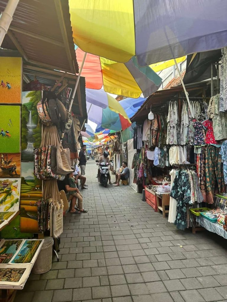 Colorful Bali market stalls with clothing and art under umbrellas