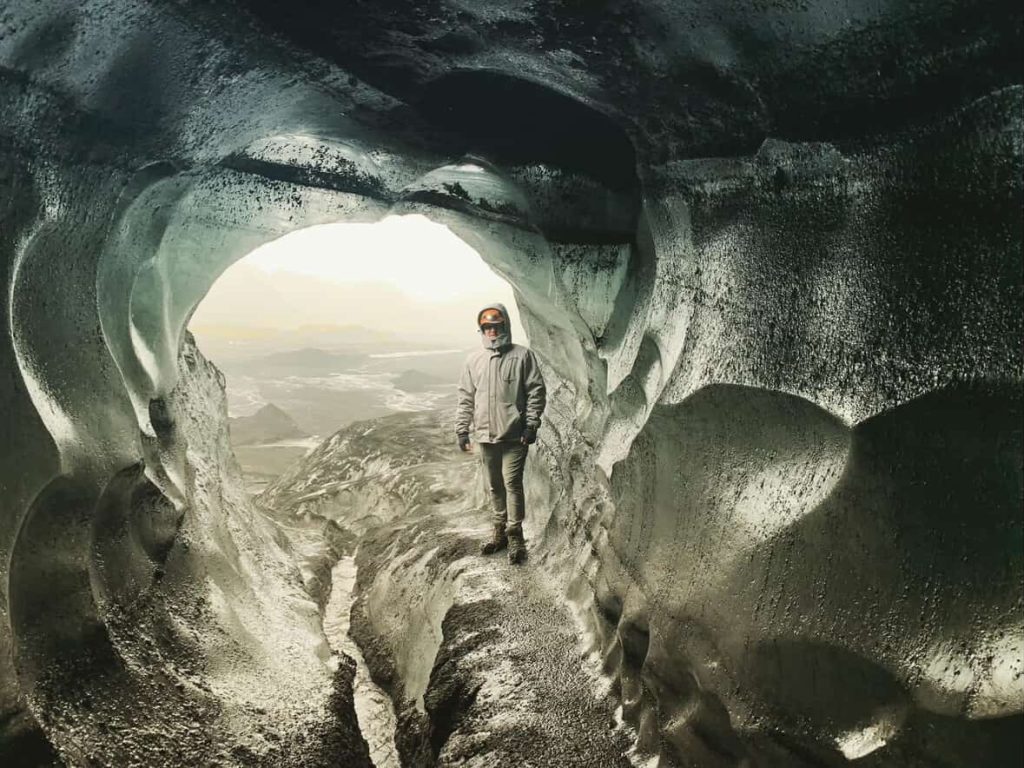 Person in ice cave near Reykjavik, Iceland. Light at cave exit.