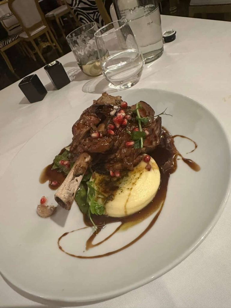 Braised lamb shank with mashed potatoes and pomegranate seeds, a fine dining dish in Cape Town.