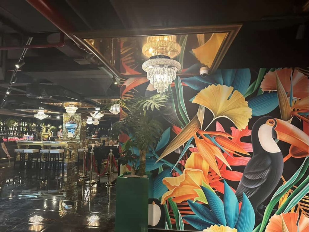 Vibrant toucan mural and crystal chandeliers in a stylish Cape Town bar