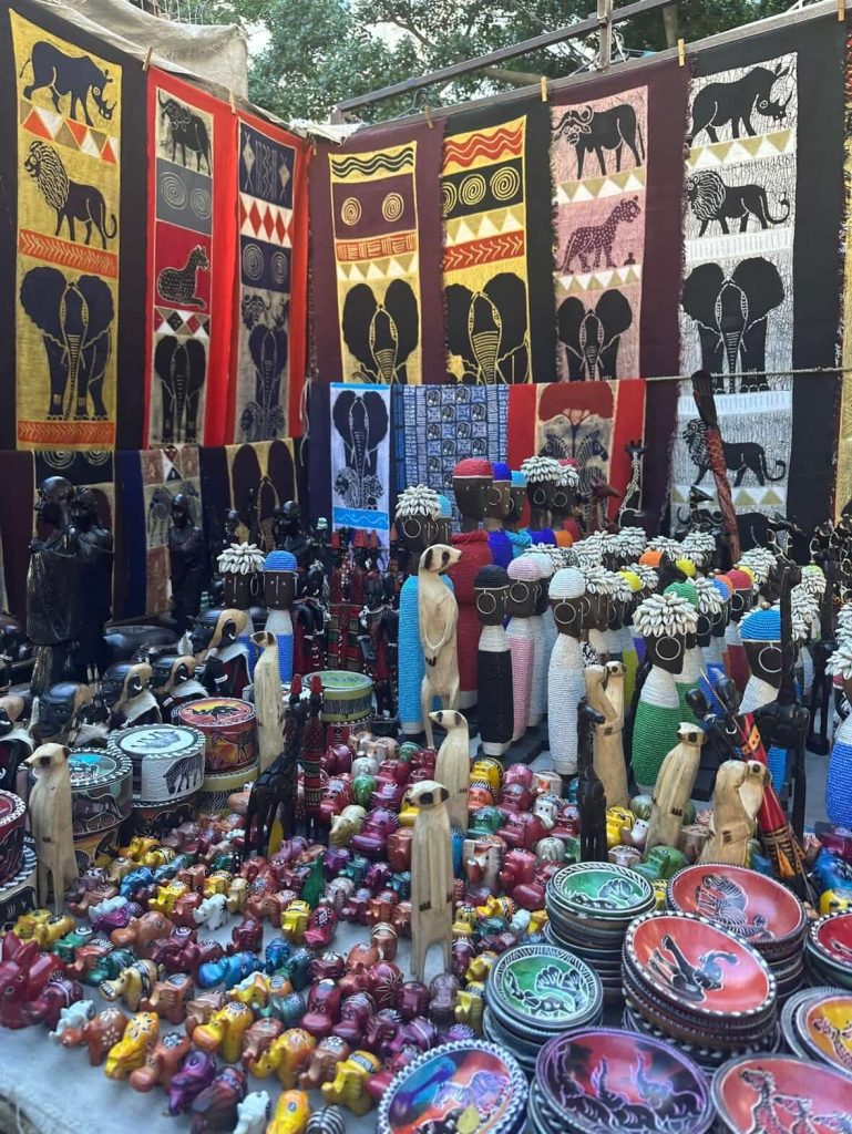 Colorful African market stall in Cape Town with animal carvings and textiles.