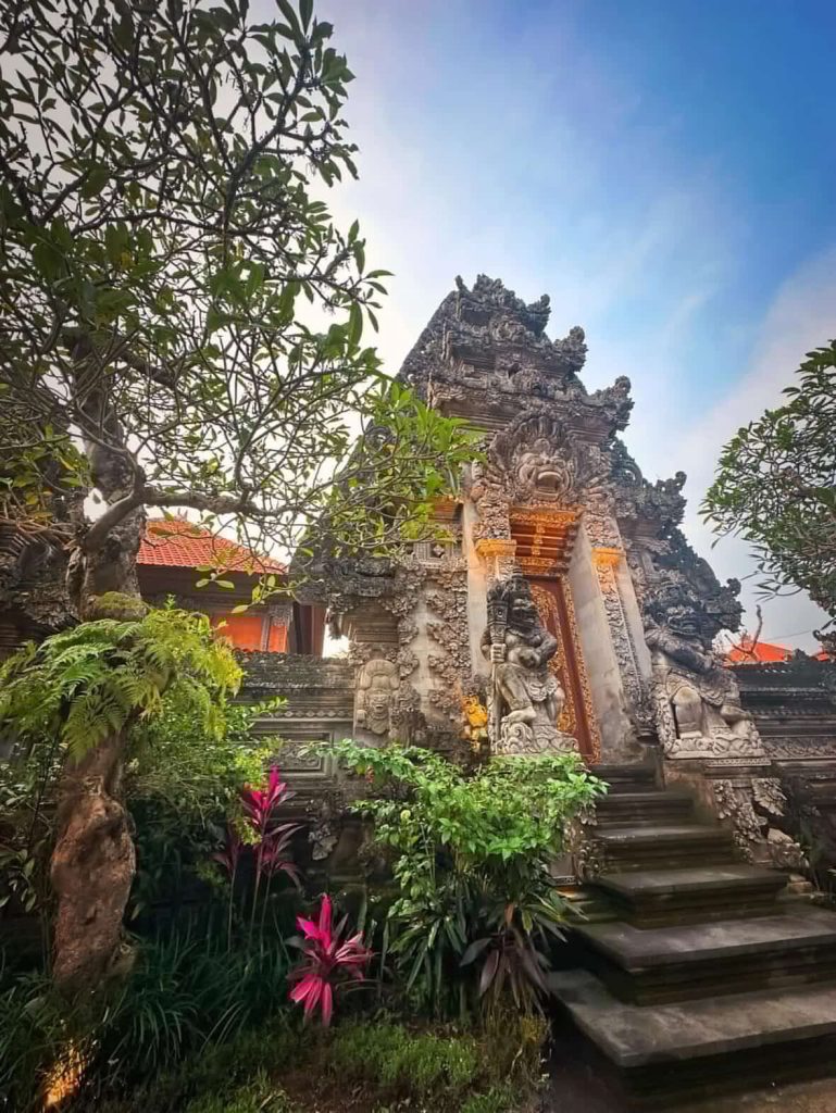 Ornate Balinese temple entrance with intricate stone carvings and lush greenery.