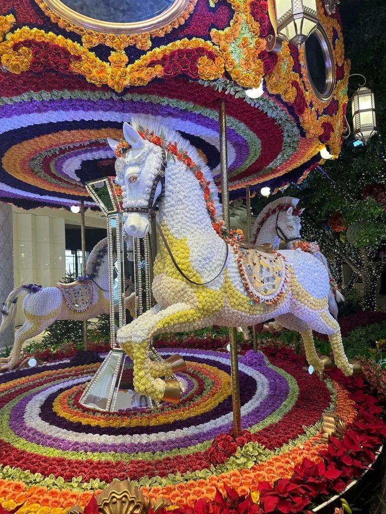 Floral carousel in Las Vegas, featuring horses adorned with flowers and a colorful, swirling base and canopy.