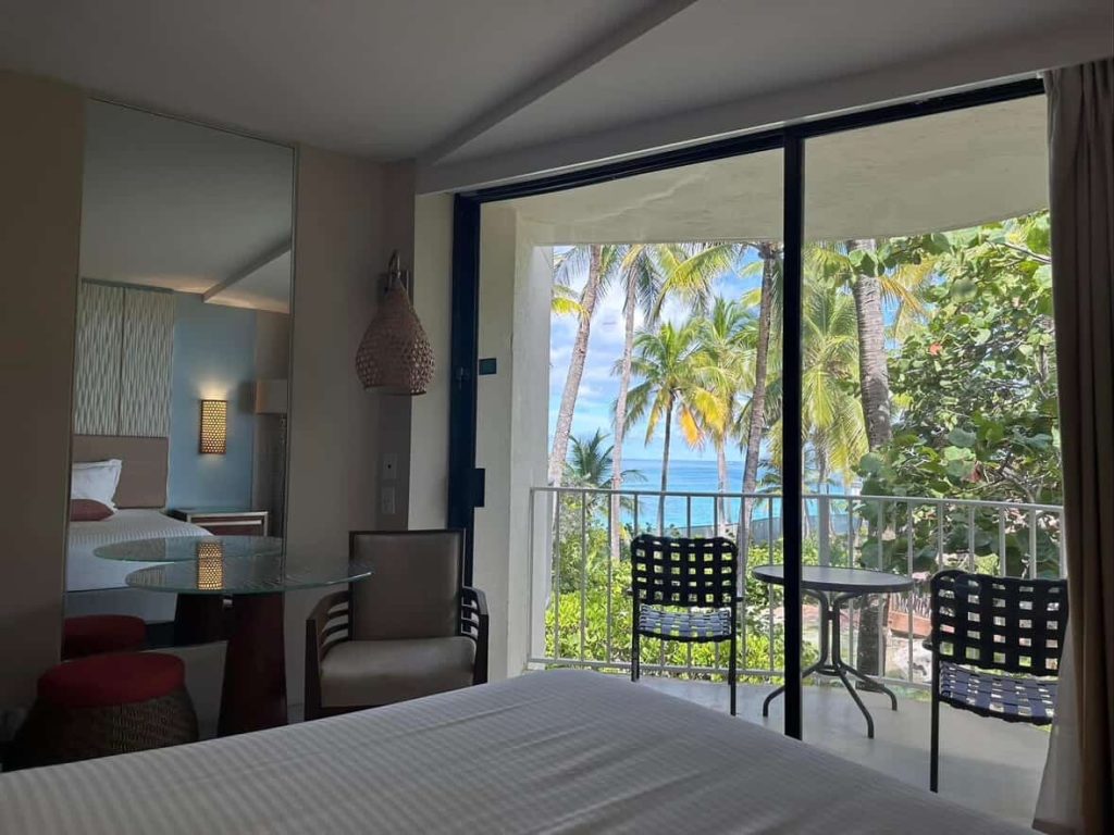 Hotel room with balcony overlooking palm trees and the ocean in Nassau