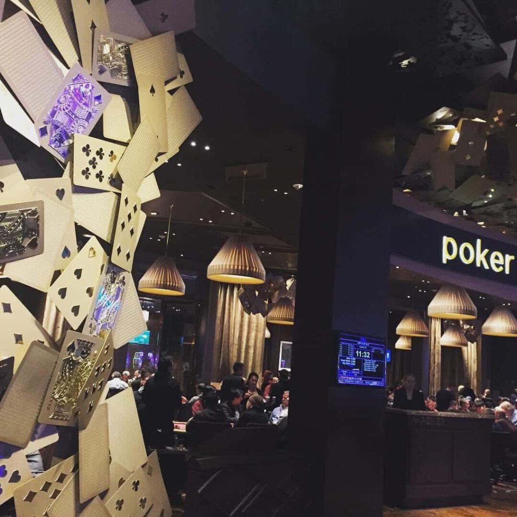 Las Vegas poker room with card decorations and players at tables.