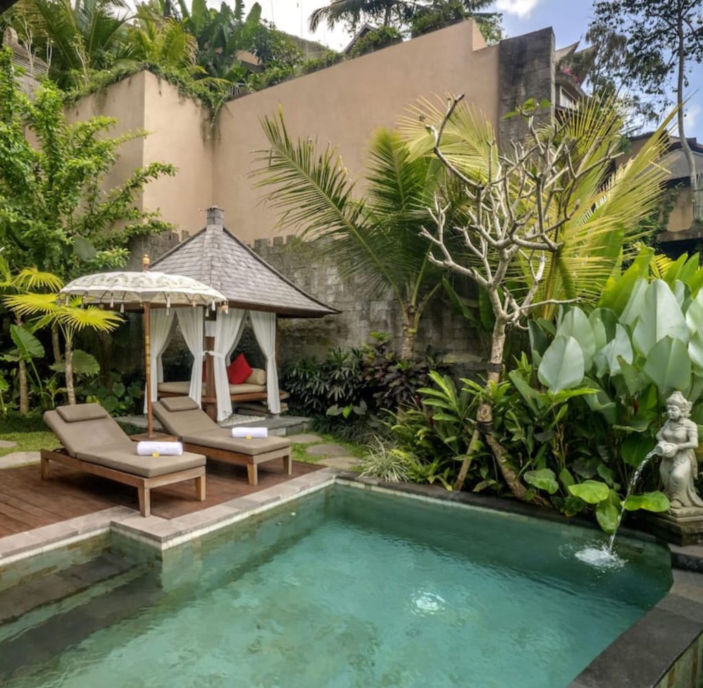 Bali villa pool with lounge chairs and tropical garden