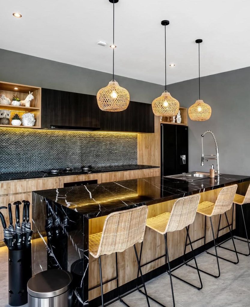 Modern Bali kitchen with a black marble island and rattan bar stools.