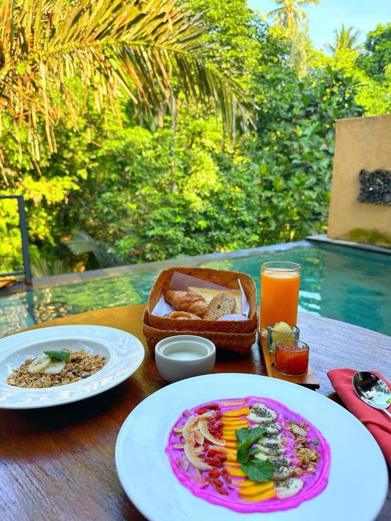 Healthy Bali breakfast with granola, smoothie bowl, and croissants by the pool
