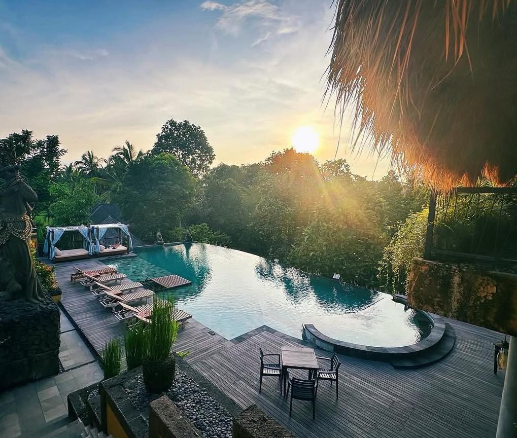 Infinity pool at a Bali resort at sunset, with lush jungle views.