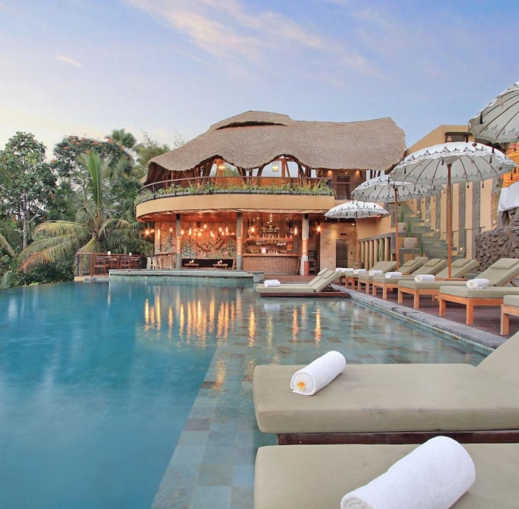 Luxury Bali resort pool with thatched-roof bar and lounge chairs