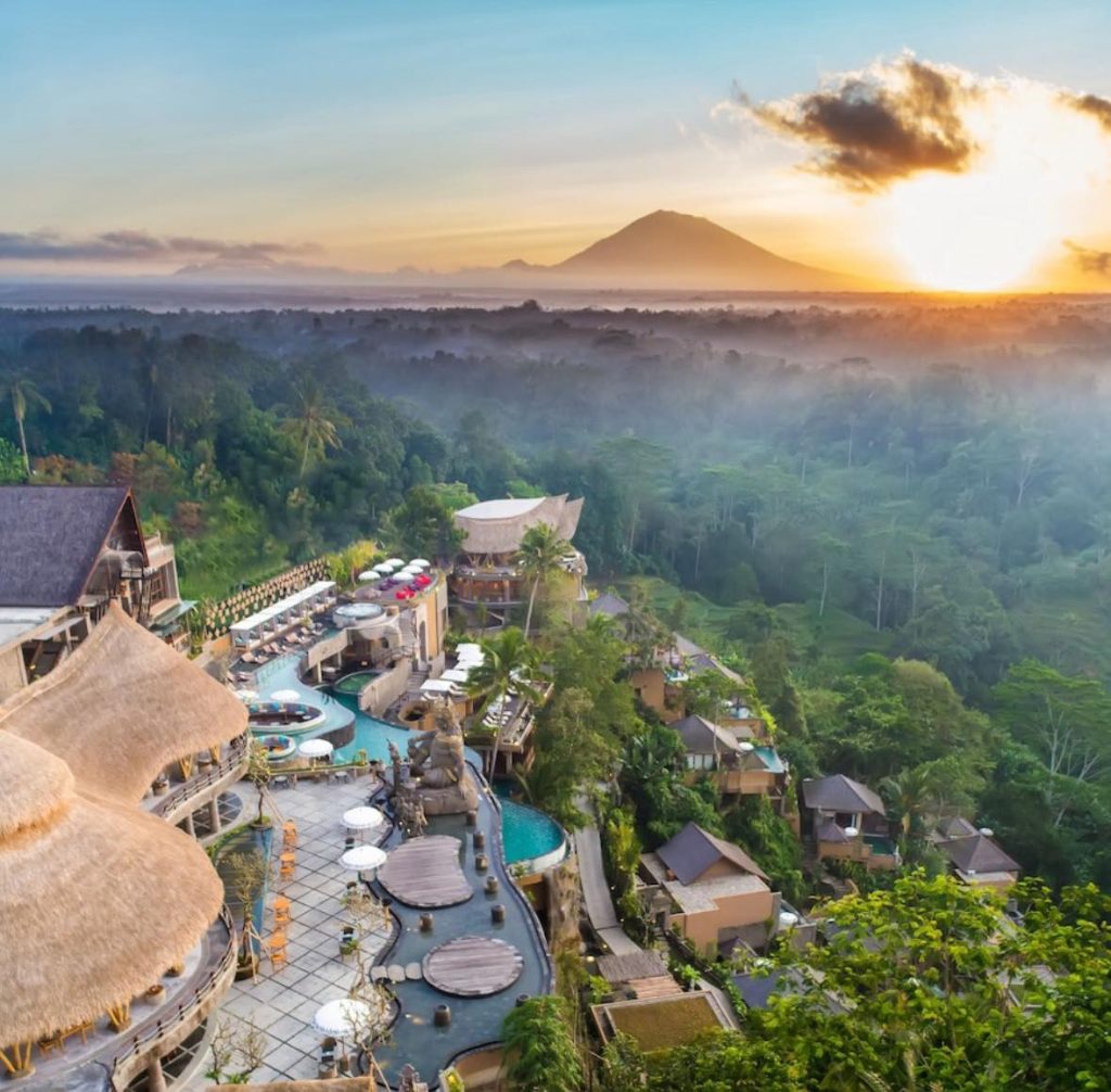 Luxury Bali resort at sunrise overlooking lush jungle and volcano