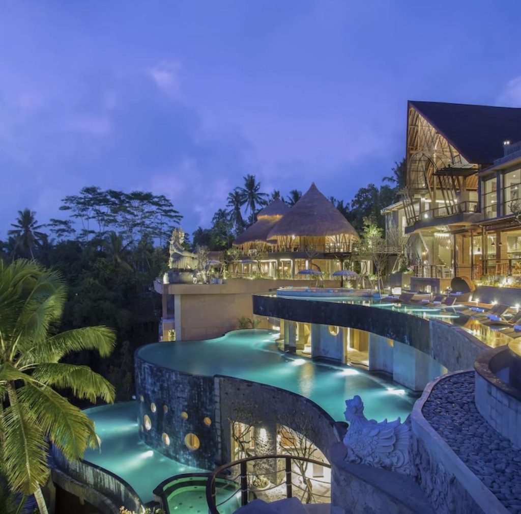 Luxury Bali resort at dusk with infinity pool and lush jungle backdrop