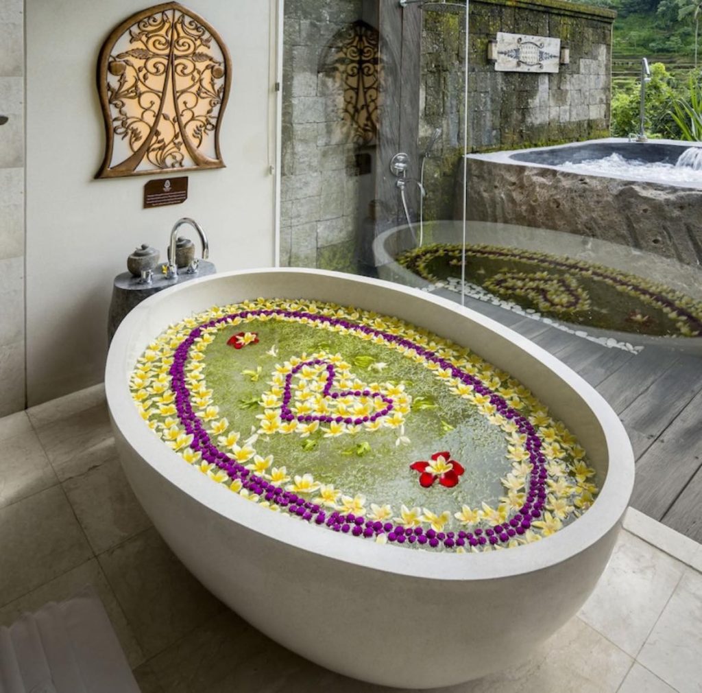 Oval bathtub filled with water and flowers, Bali spa experience