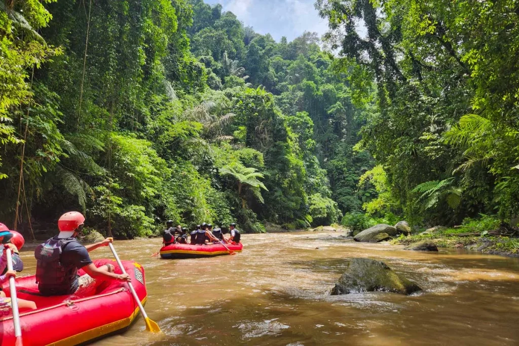 Rafting adventure in lush Bali jungle with people in red raft.