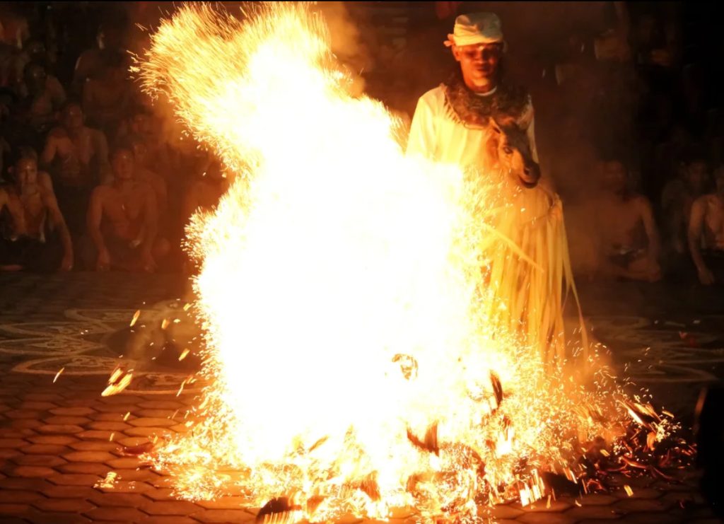 Balinese man in white performing a fire dance ritual