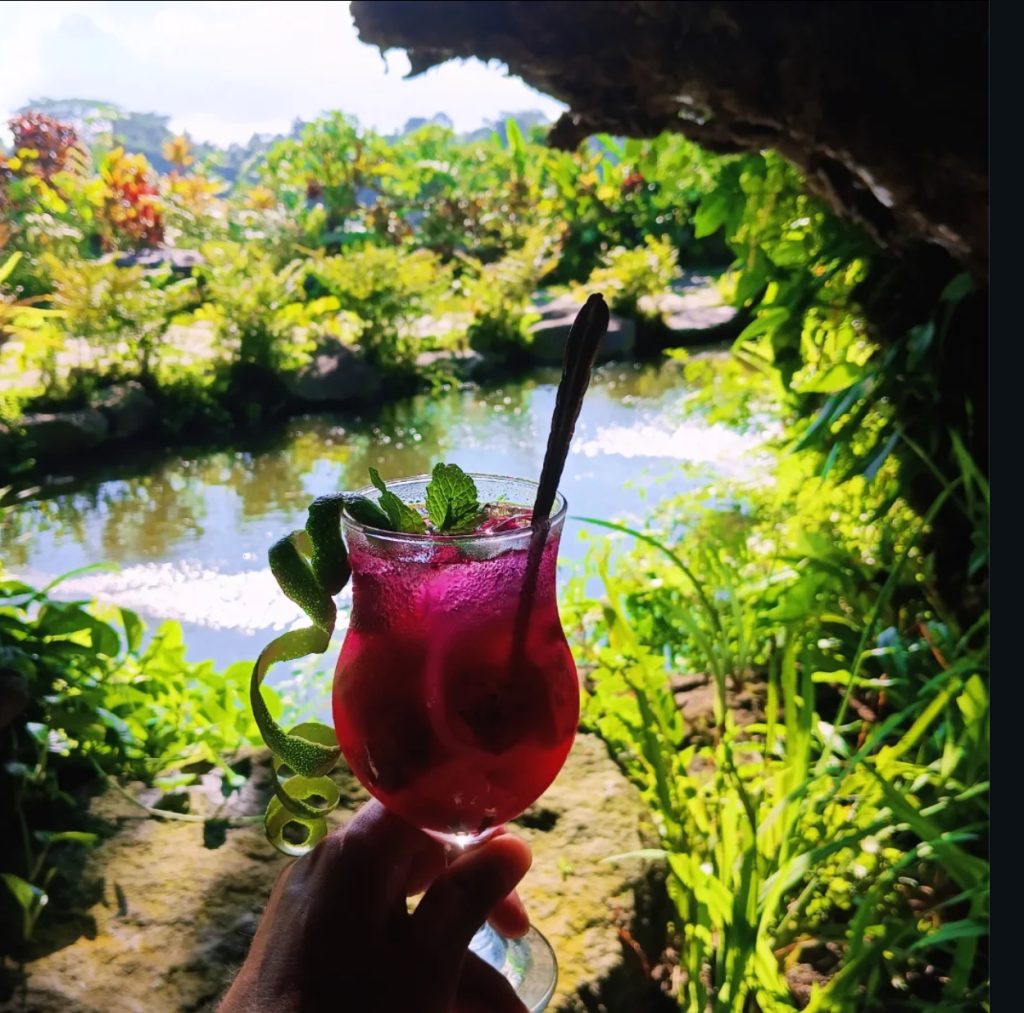 Bali cocktail with mint and lime garnish overlooking lush greenery and water.