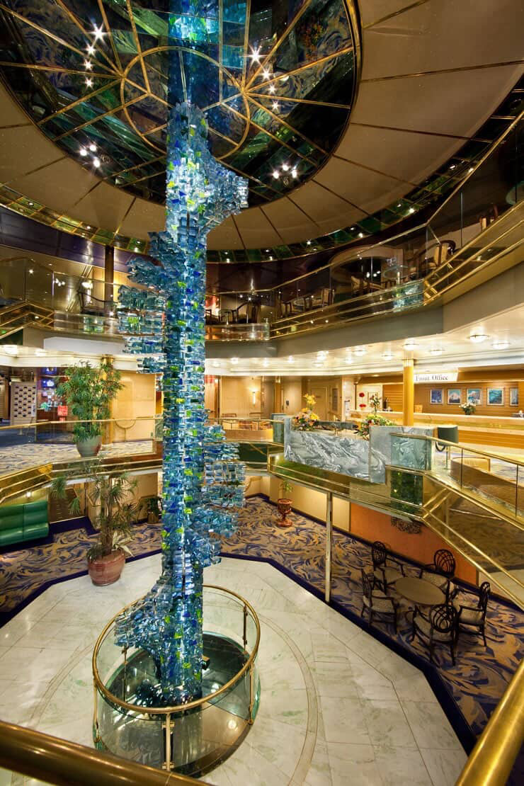 Cruise ship atrium with a stunning glass sculpture and multi-level decks.