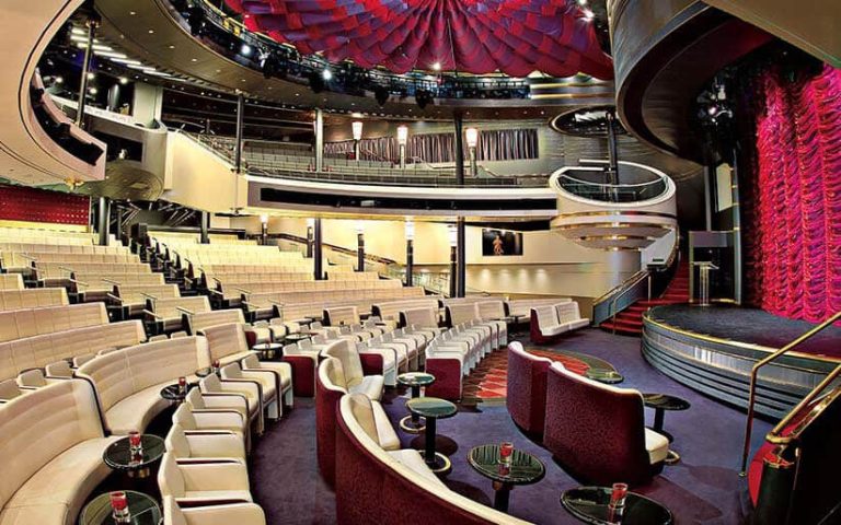 Cruise ship theater with plush seating and stage.