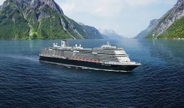 Cruise ship sailing through a fjord with mountains on either side.