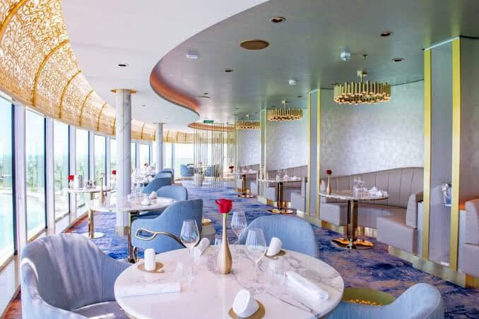 Cruise ship restaurant with elegant decor, marble tables, and ocean views.