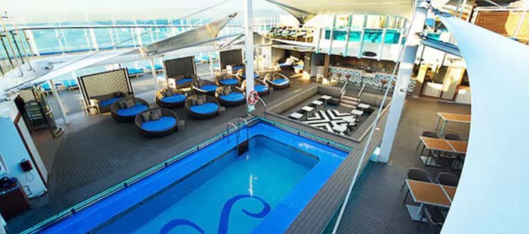 Cruise ship deck with pool, lounge chairs, and bar area.