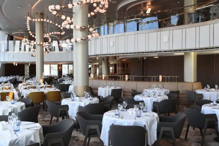 Elegant cruise ship dining room with tables set for dinner.