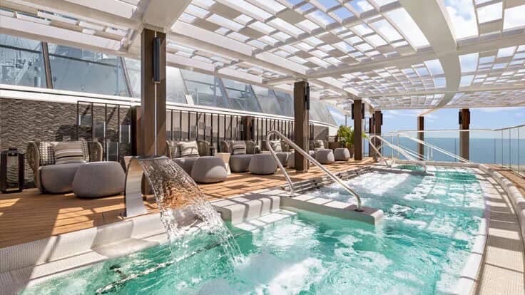 Cruise ship solarium pool with lounge seating and natural light.