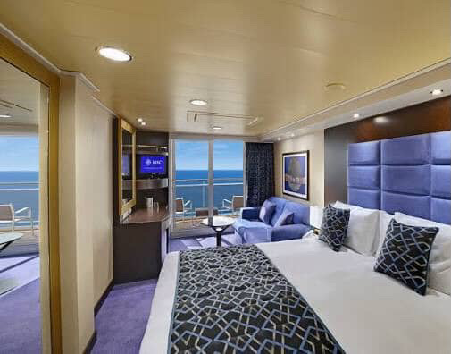 Cruise ship stateroom with balcony, ocean view, and blue accents.