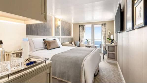 Cruise ship stateroom with balcony, bed, and ocean view. Modern, neutral decor. Balcony access.