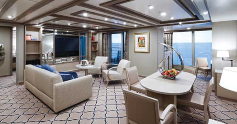 Cruise ship suite with seating, dining area, and ocean view.