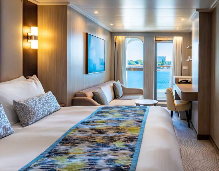 Cruise ship suite with ocean view, bed, sofa, and desk. Luxurious travel.