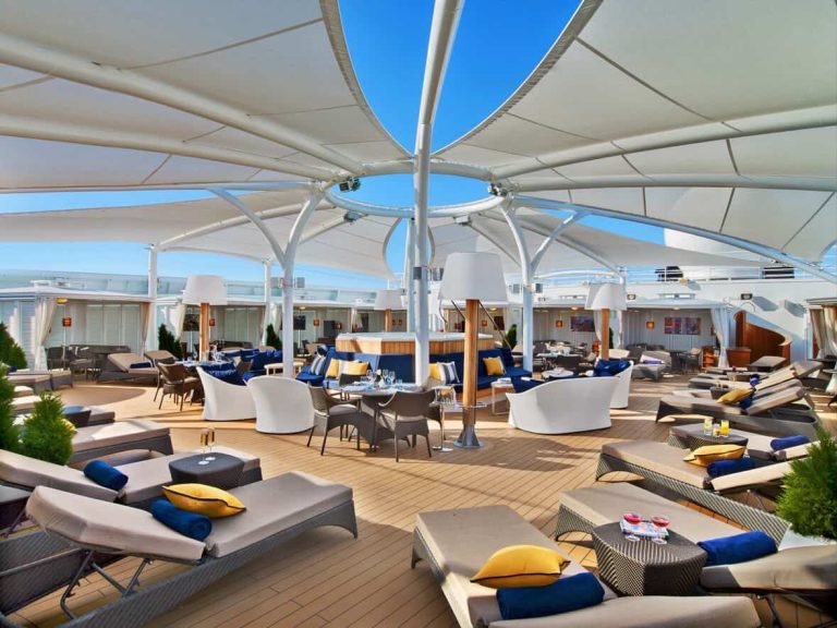 Cruise ship sundeck with loungers and sunshade.