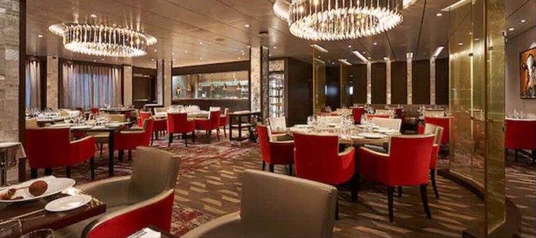 Elegant restaurant interior with red chairs, tables set, and chandeliers.