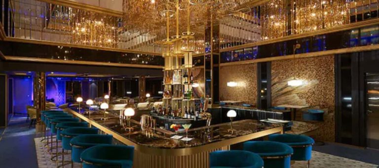 Opulent bar interior with teal seating, mirrored accents, and dramatic lighting.