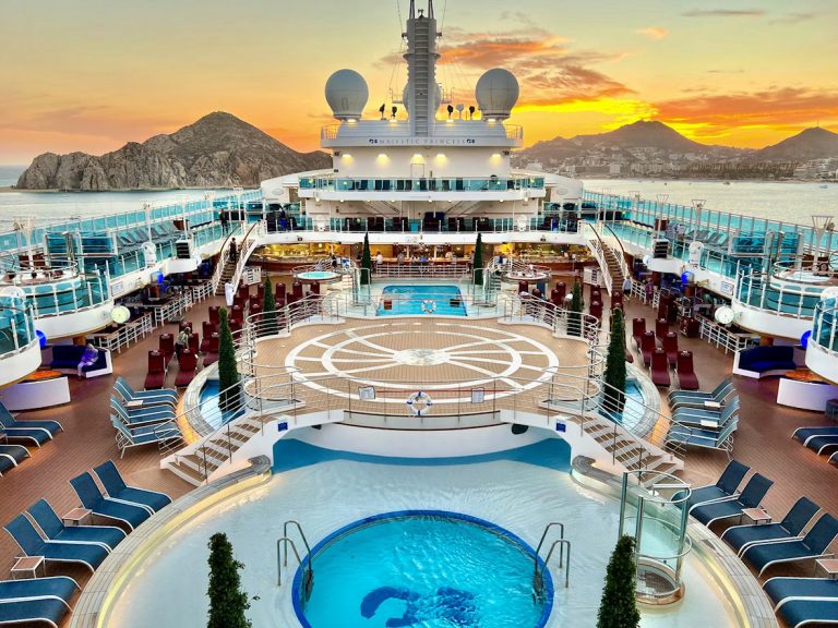 Majestic Princess cruise ship deck with pools, loungers, and ocean view at sunset.