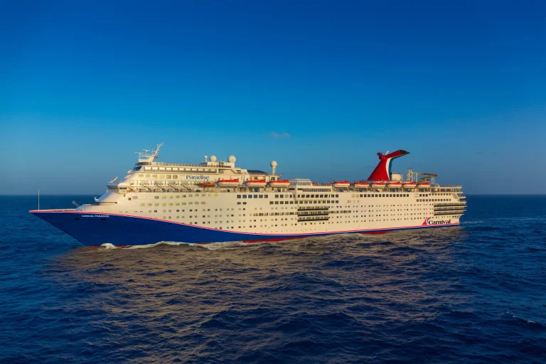 Carnival Paradise cruise ship sailing on the ocean under a clear blue sky.