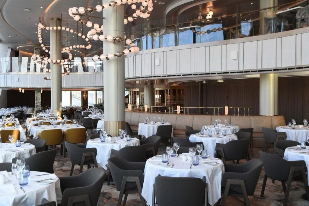 Elegant dining room with round tables set for a meal, featuring modern chandeliers.