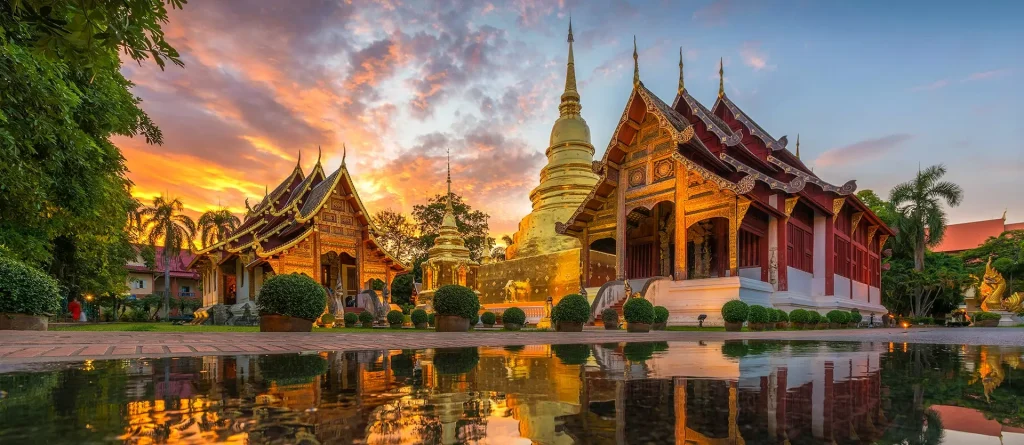 Golden Buddhist temple at sunset with vibrant sky reflection