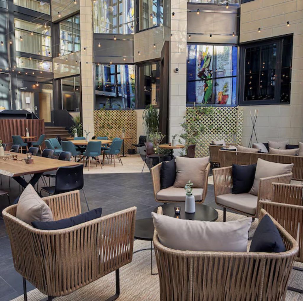 Modern hotel lobby with wicker seating, plants, and art.