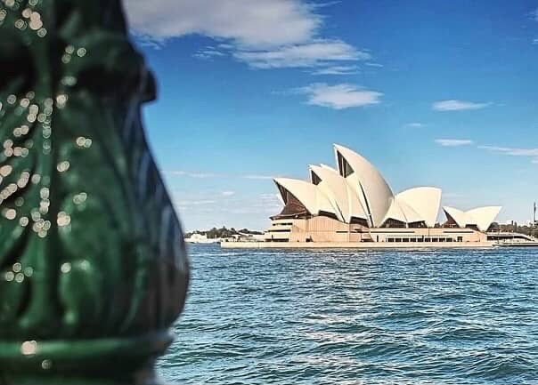 Sydney Opera House viewed across blue water on a sunny day