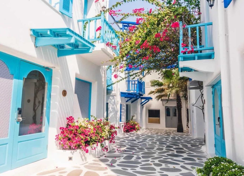 Charming white building with bright blue accents and vibrant pink bougainvillea flowers.