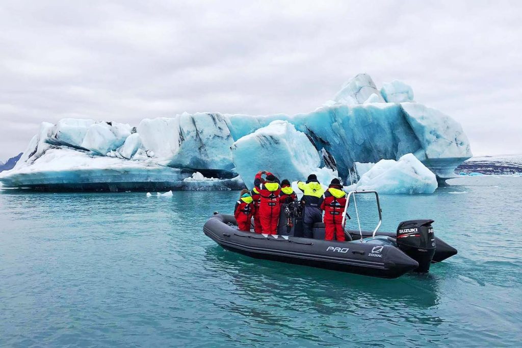 Tourists in a Zodiac boat explore icebergs in Jökulsárlón glacier lagoon, Iceland.